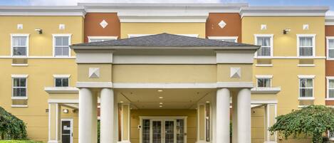 A multi-story hotel with a central entrance, columns, and a yellow facade.