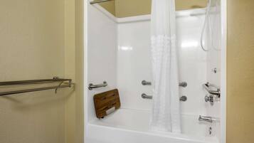 Une baignoire blanche avec un pommeau de douche, un porte-savon en bois et un porte-serviettes en métal.