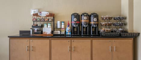 A coffee station with multiple coffee dispensers, a coffee machine, and a variety of coffee pods.