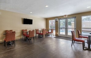 A spacious indoor area with multiple tables and chairs, a flat-screen TV mounted on the wall, and large windows providing natural light. - Extended Stay America Suites Orlando Maitland 1776 Pembrook (Orlando)