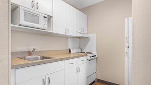 A kitchen with white cabinets, a microwave, a stove, and a refrigerator. - Extended Stay America Suites Fort Worth Fossil Creek (Fort Worth)