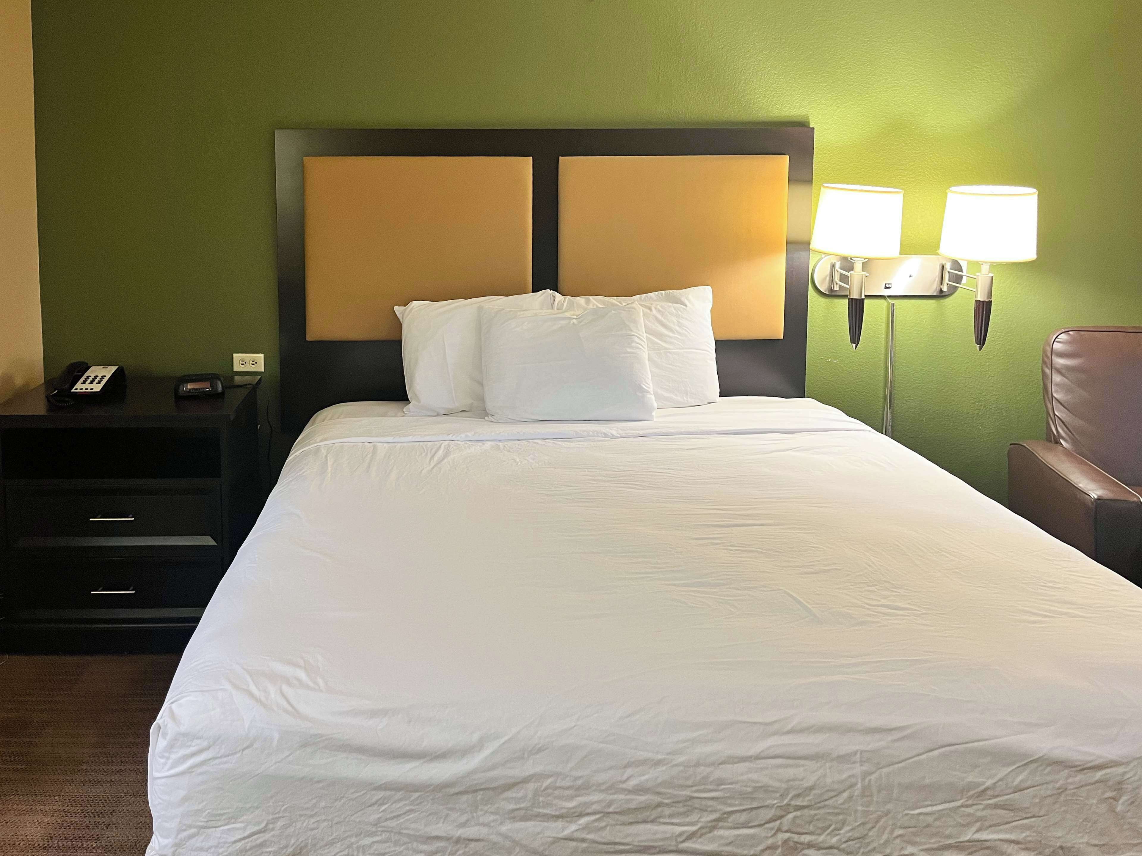 Une chambre d’hôtel avec un grand lit, deux lampes de chevet, un téléphone et une table de chevet.