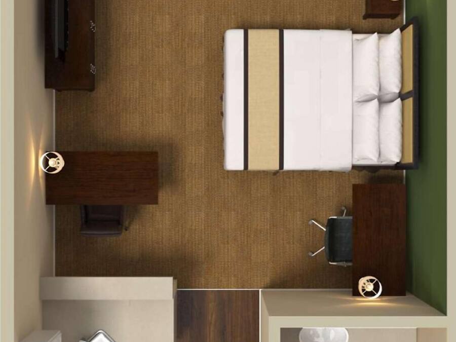Habitación de hotel pequeña y funcional, con cama, escritorio, zona de estar, baño y ventana.