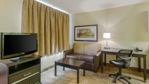 A hotel room with a flat-screen TV, a sofa, a desk with a chair, a lamp, and a framed picture on the wall. - Extended Stay America Suites Richmond W Broad St Glenside N (Richmond)
