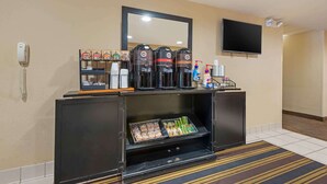 Ein Hotel-Rezeptionsbereich mit einer Kaffeestation, einem Telefon, einem Fernseher und einem Spiegel.