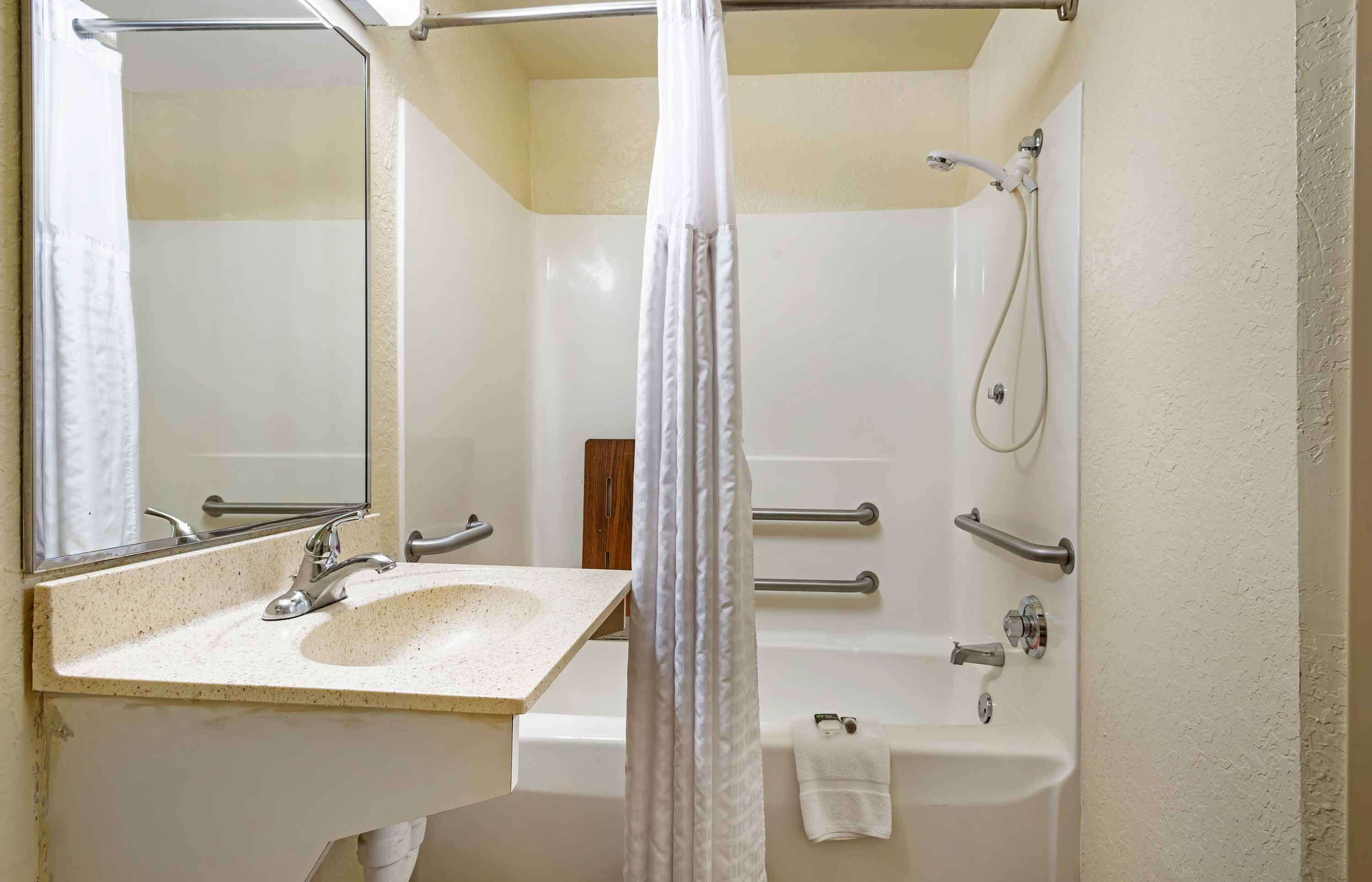 A bathroom with a sink, mirror, shower, and bathtub.