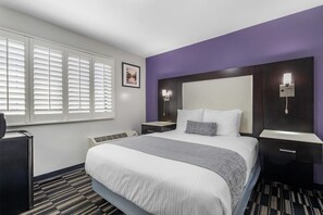 A hotel room with a large bed, a nightstand, a desk, and a window with blinds. - SureStay Hotel by Best Western Beverly Hills West LA (Los Angeles)