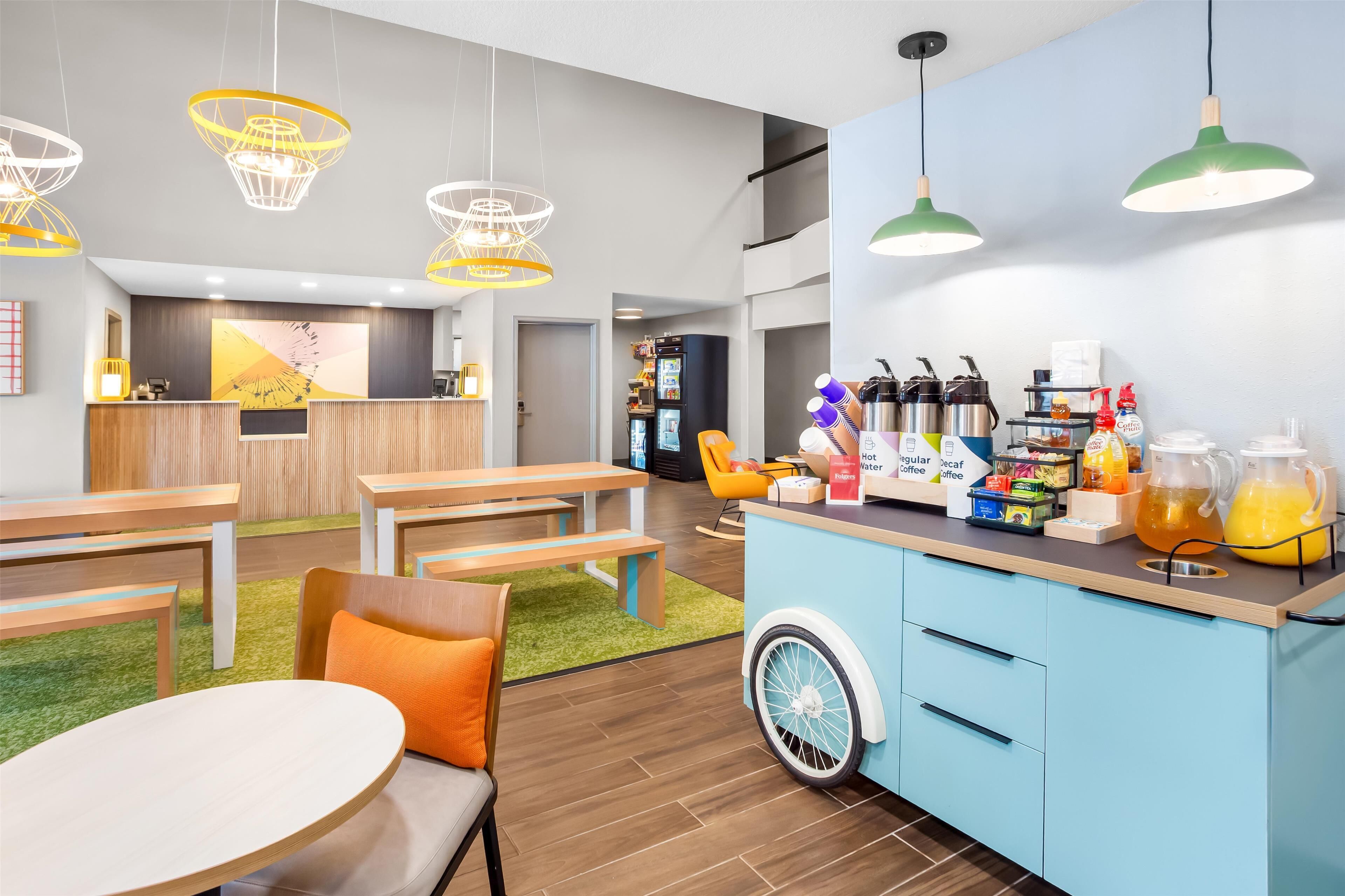 Un caffè moderno con mobili in legno, un bancone blu e una selezione di bevande.