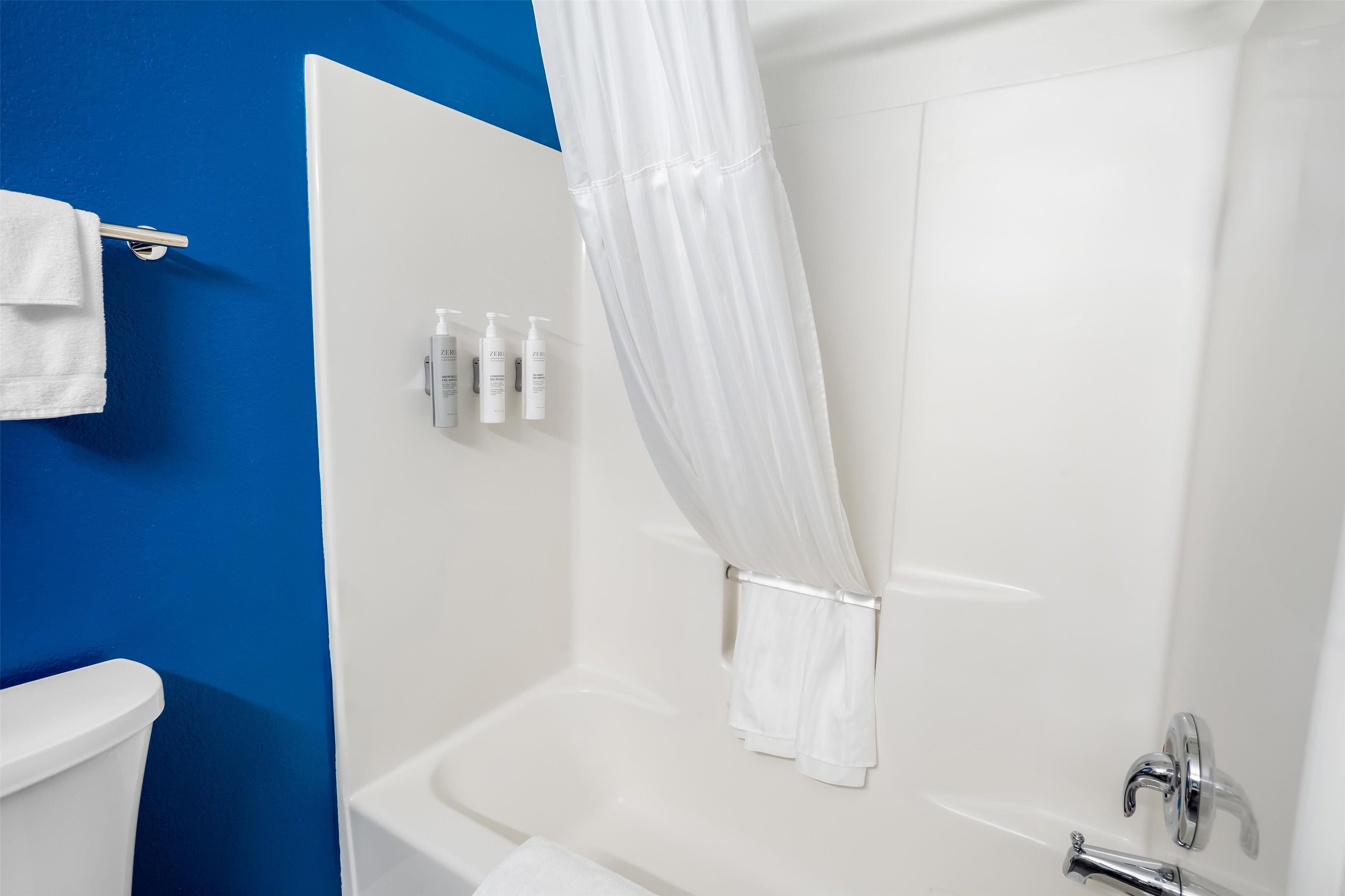 Un bagno con una vasca da bagno bianca, un muro blu e un asciugamano bianco appeso a un portascopevoli.