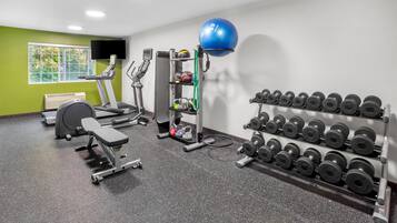 Un gimnasio con cinta de correr, banco para pesas, pesas sueltas y pelota medicinal.