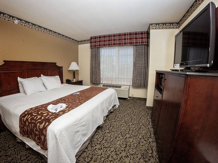 A hotel room with a bed, a desk, a television, and a window with curtains.