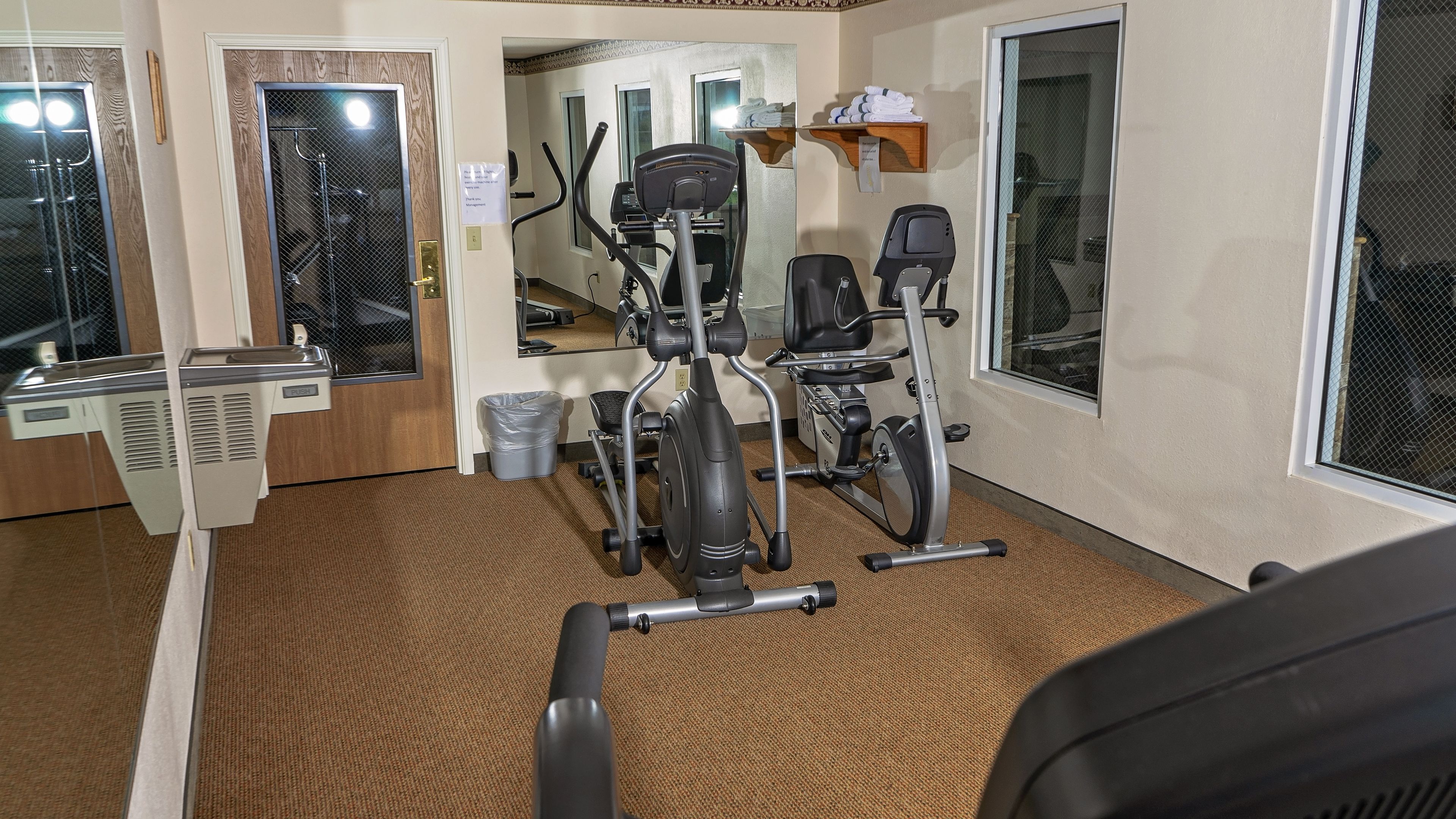 A gym with stationary bikes, a treadmill, and a mirror.