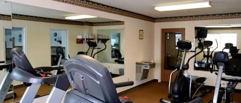 Une salle de sport équipée de tapis de course, de vélos d’appartement et d’appareils de musculation elliptique.