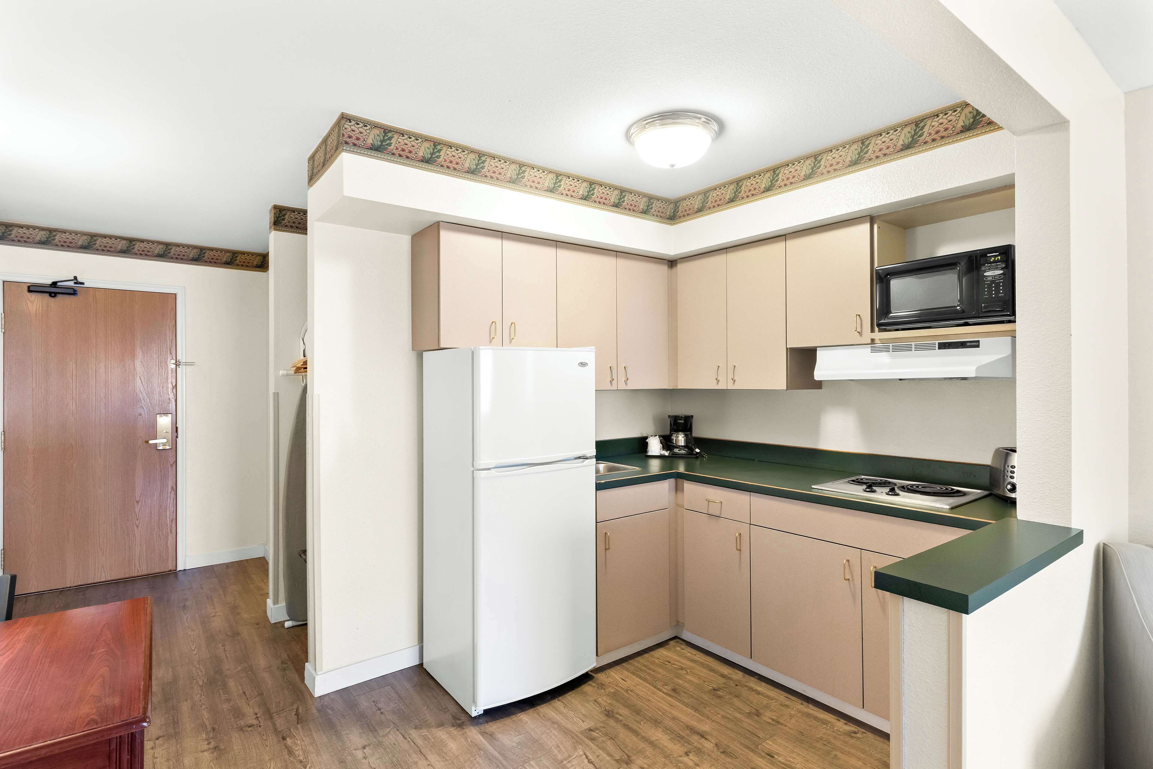 A compact kitchen with a refrigerator, microwave, and stove.