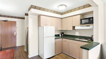 A compact kitchen with a refrigerator, microwave, and stove.