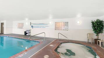 An indoor swimming pool with two separate sections, a tiled wall with a window, and a potted plant.