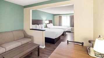 A hotel room with a sofa, a wooden table, a bed, and a desk.
