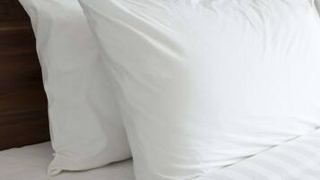 Ein Bett mit weißer Bettwäsche und einem gestreiften Kopfkissen.