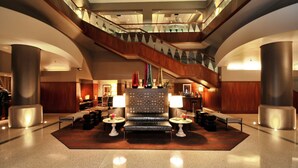 A spacious lobby with a central seating area, a staircase, and a reception desk. - Magnolia Hotel Dallas Downtown (Dallas)