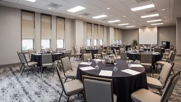 Une salle de conférence équipée de tables rondes, de chaises et d’un écran de projection.