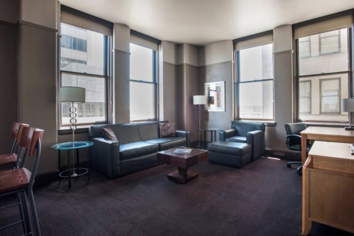 Ett modernt hotellrum med ett stort fönster, en soffa, ett soffbord och ett skrivbord.