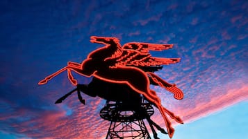 Silueta de una estatua ecuestre sobre una estructura alta, con el cielo al atardecer.