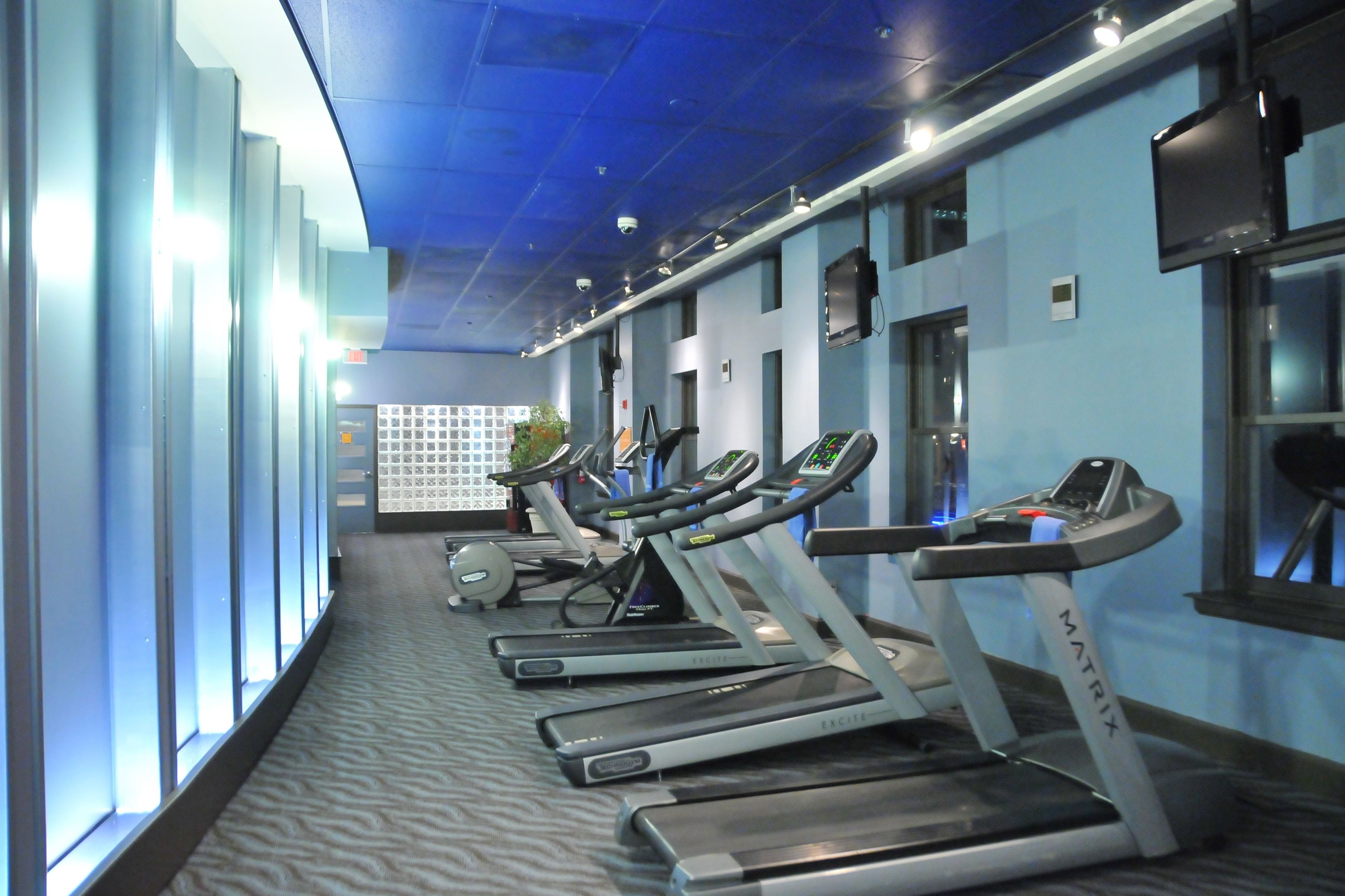 A gym with treadmills, exercise balls, and a wall-mounted TV.