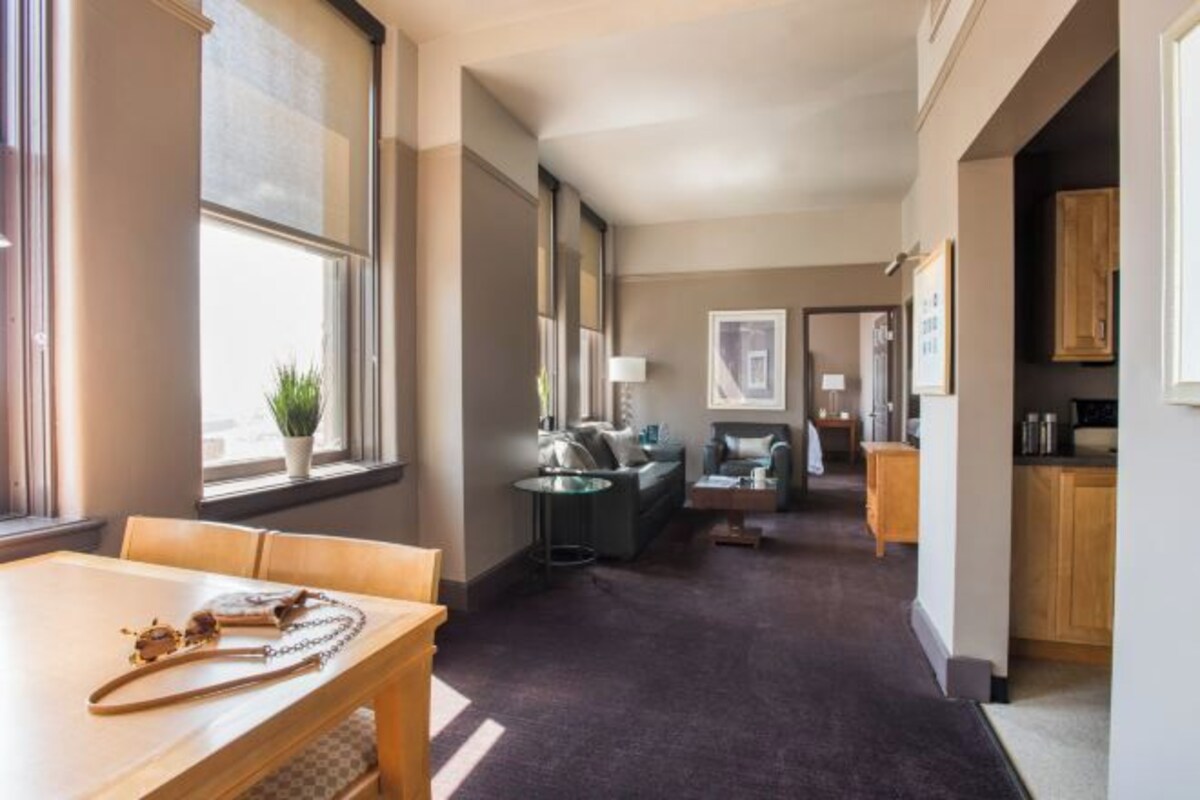 Ett hotellrum med en matplats, en soffa, ett litet bord och ett köksutrymme.