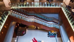 A spacious lobby with a central seating area, multiple staircases, and a modern design. - Magnolia Hotel Dallas Downtown (Dallas)