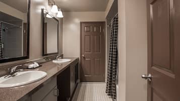 A bathroom with two sinks, a large mirror, and a shower area.