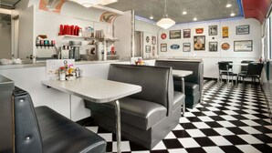 Un restaurant avec des banquettes et des tables, un sol à carreaux et des décorations murales.