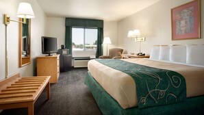 Une chambre d’hôtel équipée d’un lit, d’un bureau, d’une chaise, d’une télévision et d’une fenêtre donnant sur un paysage agréable.