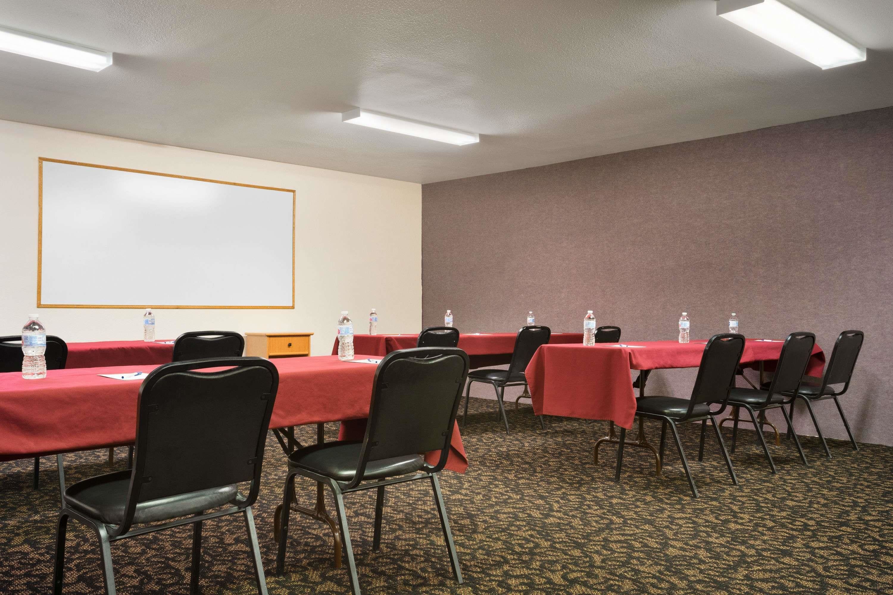 A conference room with tables and chairs, a projector screen, and water bottles on the tables.