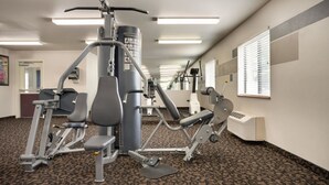 Une salle de sport équipée de matériel d’exercice, un comptoir d’accueil et un tapis à motifs.