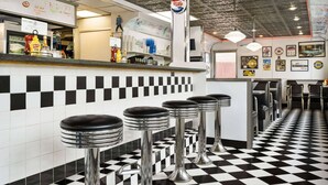 A diner with a retro design, featuring checkered flooring, classic bar stools, and a menu board with handwritten notes. - Baymont by Wyndham Hearne (Hearne)