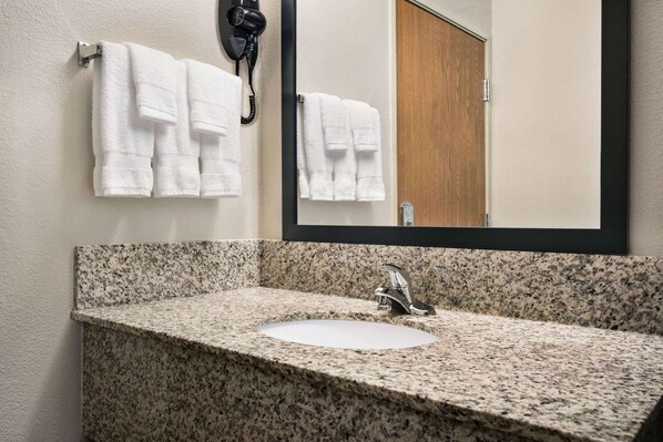 A bathroom with a granite countertop sink, a mirror, and two white towels hanging on the wall.