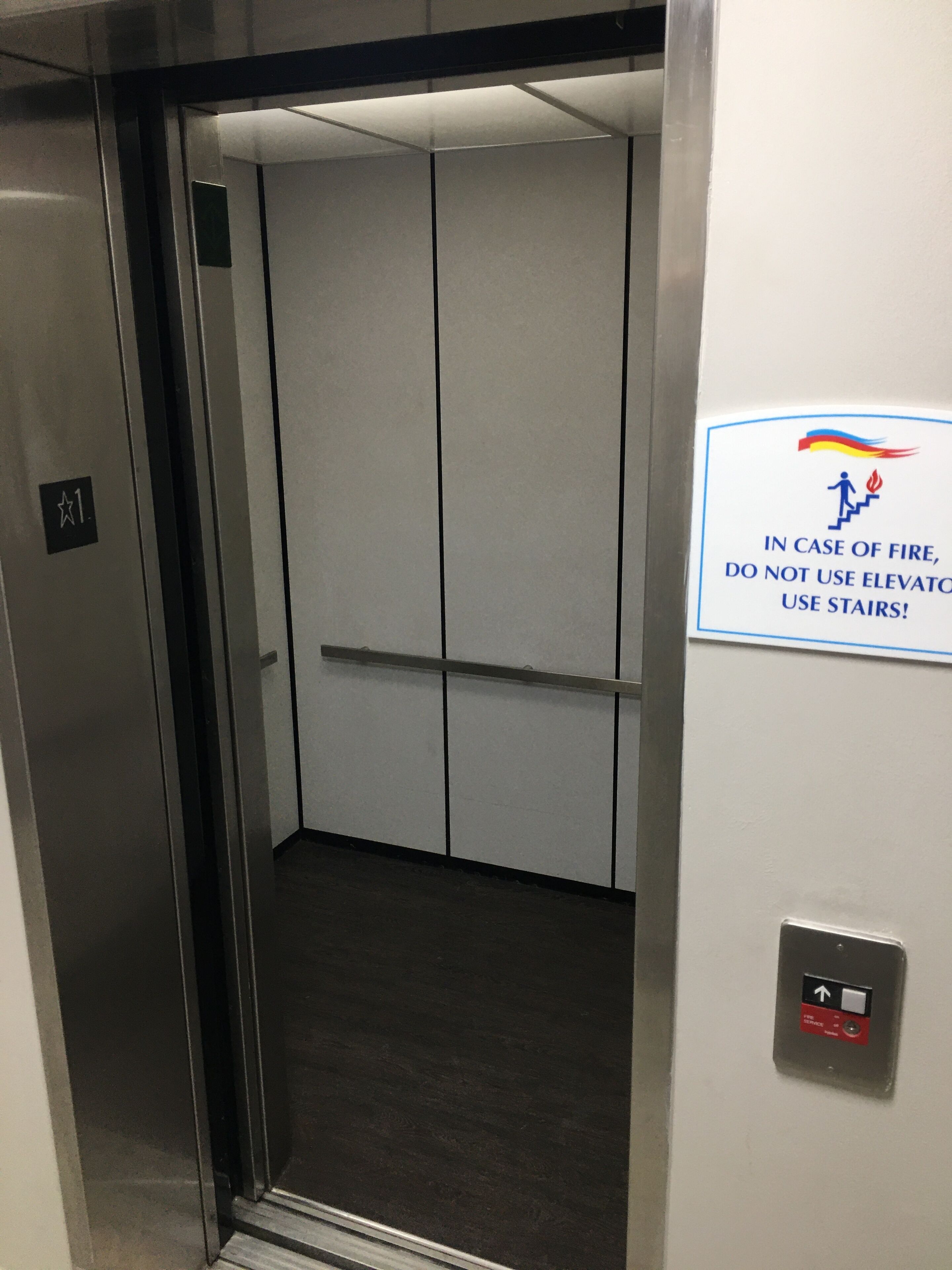 An elevator interior with a sign instructing to use stairs in case of fire.