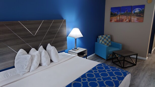 Una habitación de hotel con una cama grande, una pared azul, un sofá azul y un cuadro de un paisaje urbano.