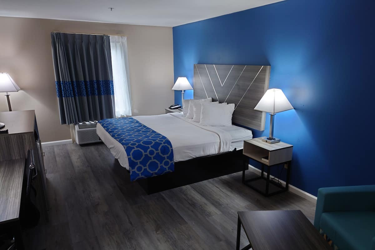 Una habitación de hotel con cama, lámparas de noche, escritorio, silla y sofá.
