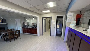 Un vestíbulo de hotel con comedor, cocina y mostrador de recepción.
