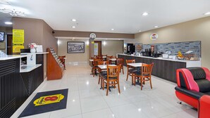 A restaurant with a counter, chairs, and a clock on the wall.