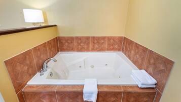 A bathroom with a freestanding bathtub, a wall-mounted light, and a towel on the edge.