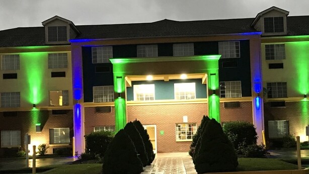 A multi-story building with a central entrance, surrounded by well-maintained bushes and a paved walkway. - Days Inn by Wyndham Norton (Norton)
