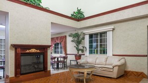 A spacious living area with a fireplace, a round coffee table, a sofa, and a dining table with chairs. - Days Inn by Wyndham Norton (Norton)