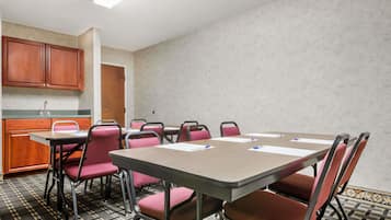 A conference room with a long table, multiple chairs, a kitchenette, and a patterned floor.