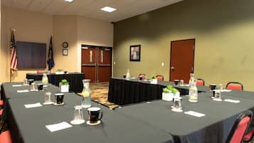 A conference room with tables set for meetings, flags, and a clock on the wall.