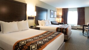 A hotel room with two beds, a desk, a chair, and a window with curtains.