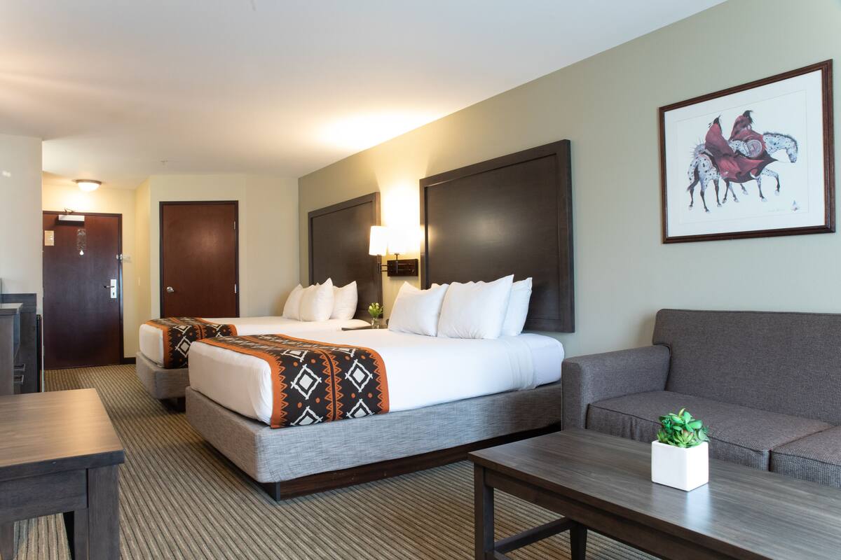 A hotel room with a large bed, a sofa, a coffee table, and a framed picture on the wall.