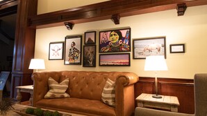A brown leather sofa with striped pillows, a wooden coffee table with decorative items, and a framed artwork collection on the wall.