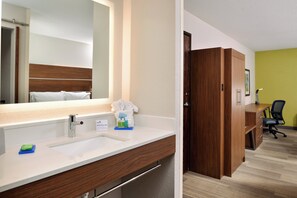 A hotel bathroom with a sink, mirror, and toiletries.